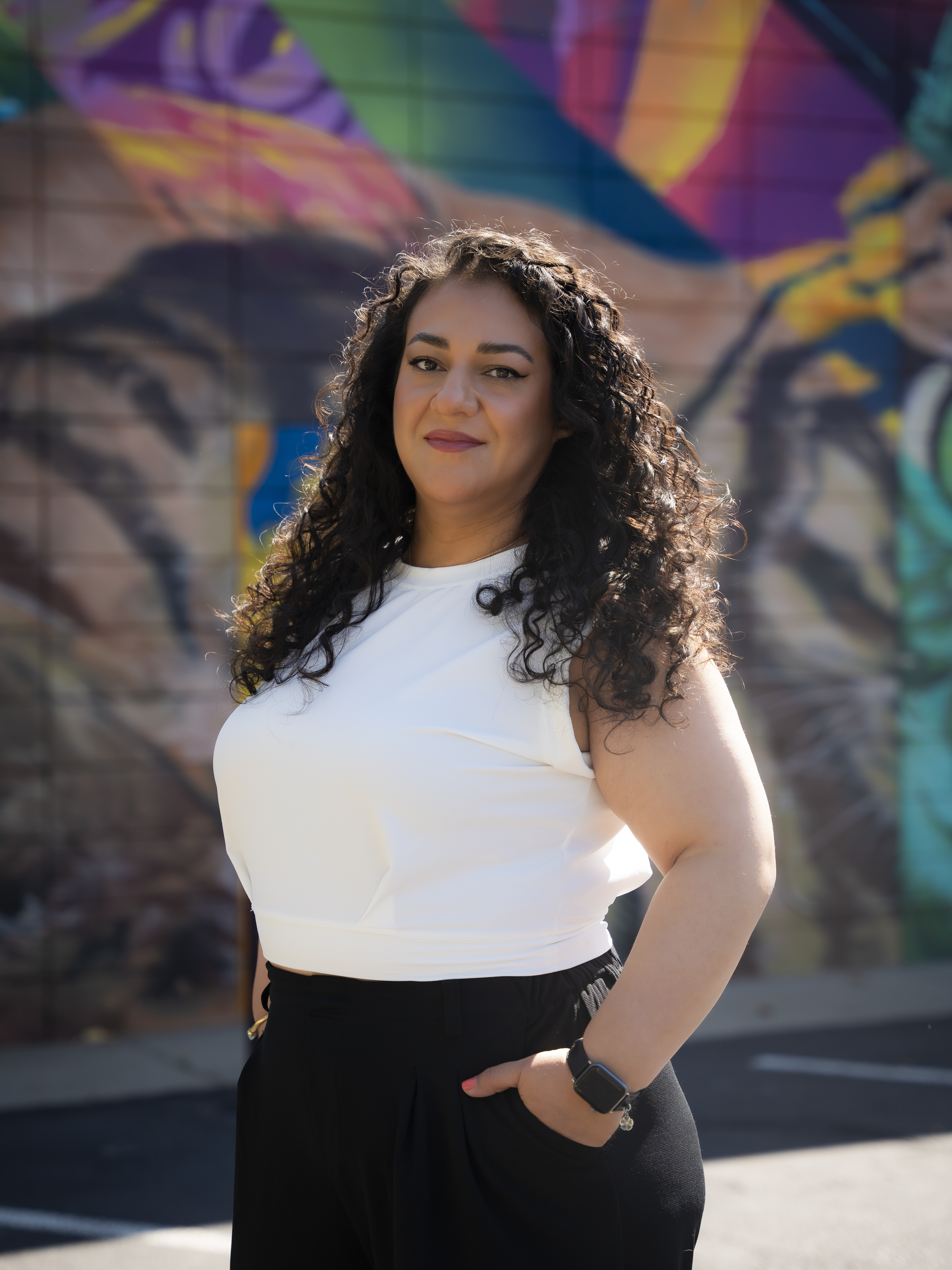 Jenny Butler, Marketing Manager standing in front of a large mural