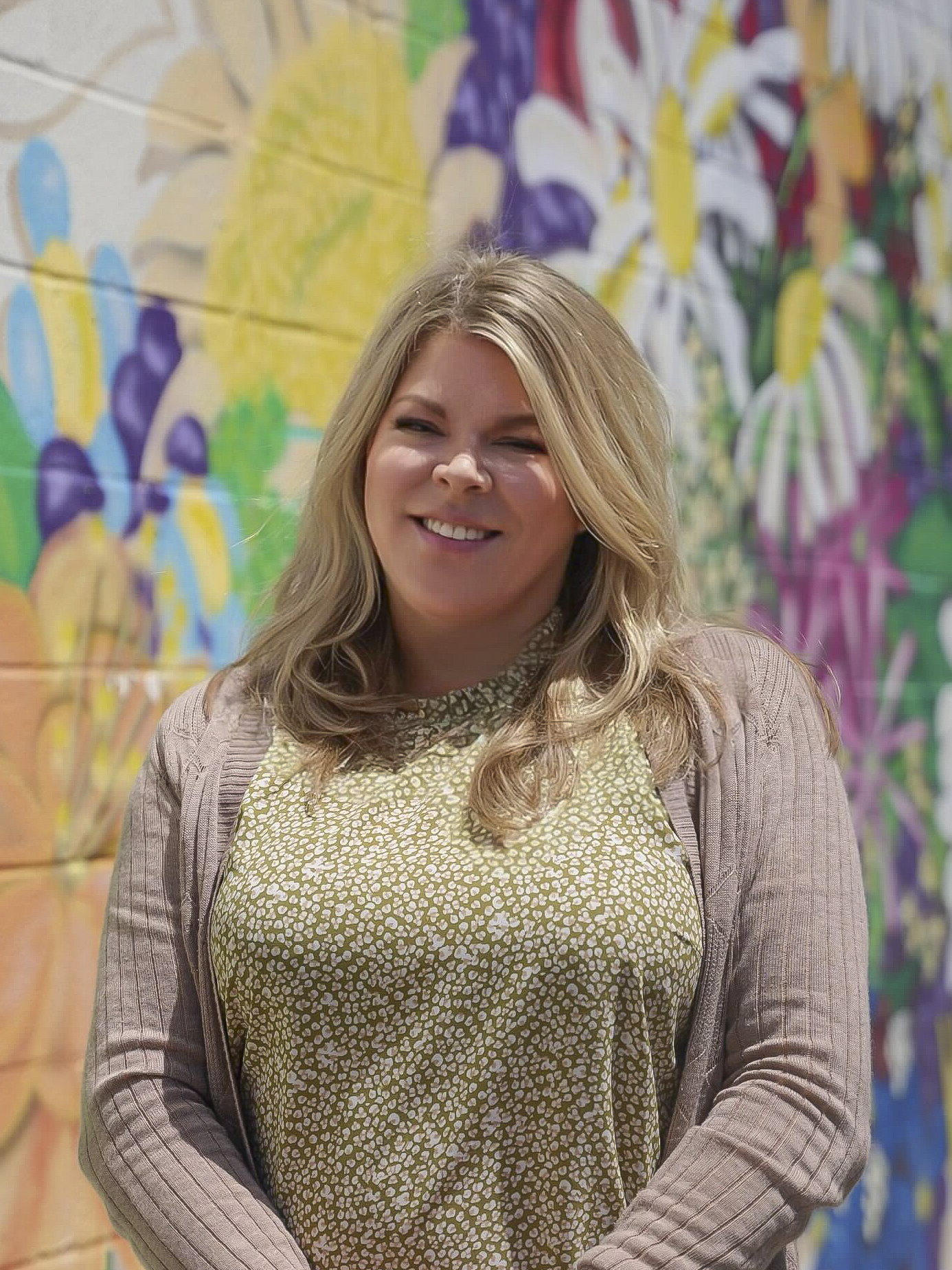 Tammy Cruise, Office Manager standing in front of large mural